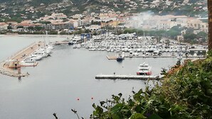 A marina with numerous boats docked, surrounded by residential buildings and mountains in the background.