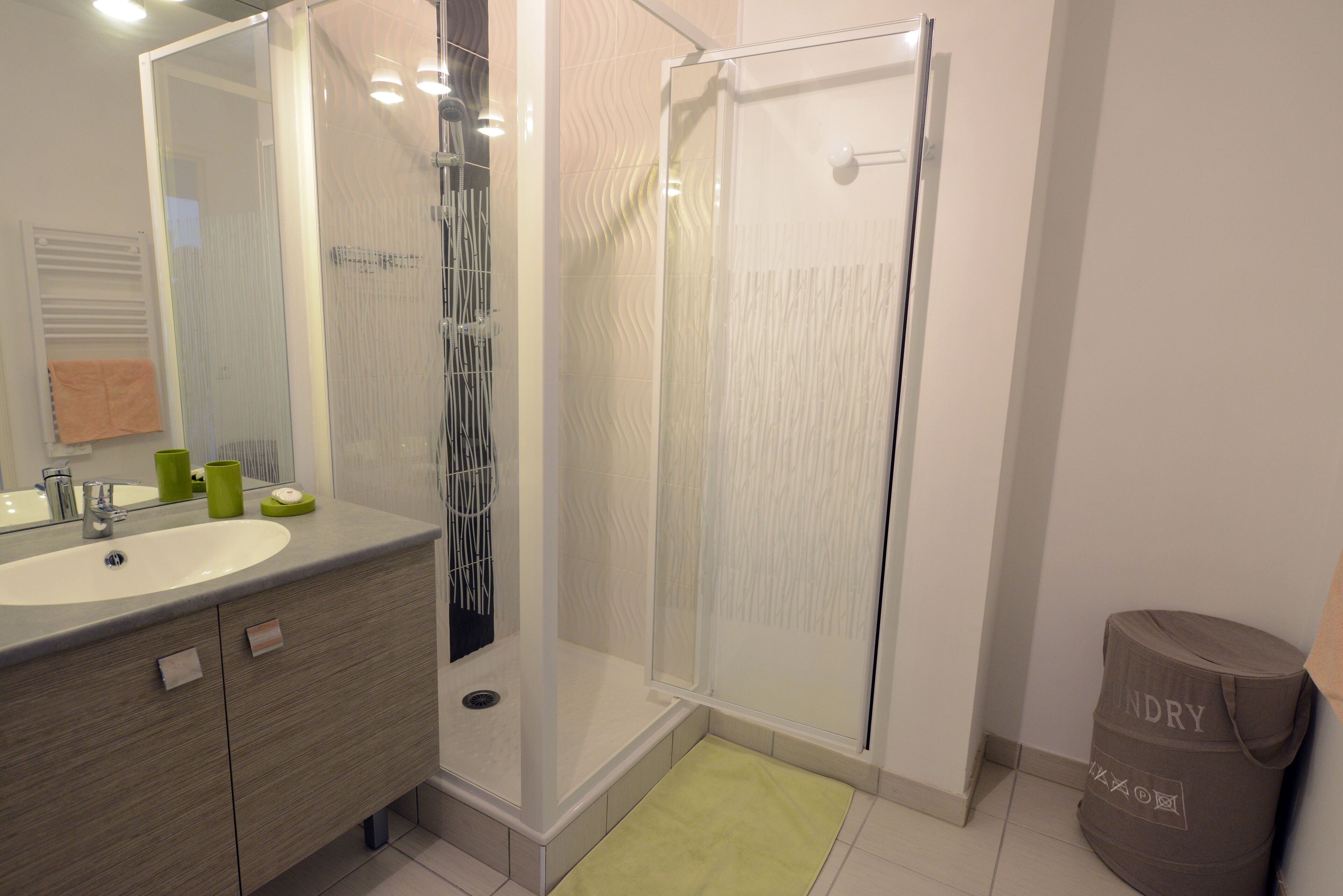 Un baño moderno con cabina de ducha de vidrio, un lavamanos con espejo y un perchero para toallas.