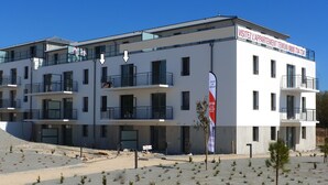 Un immeuble à plusieurs étages doté de balcons, d’une enseigne et d’un drapeau.