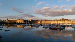 Un port où de nombreux bateaux sont amarrés, un fort historique et un ciel dégagé.
