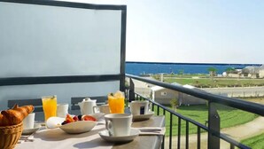 Un balcon aménagé pour le petit-déjeuner, avec vue sur la côte.