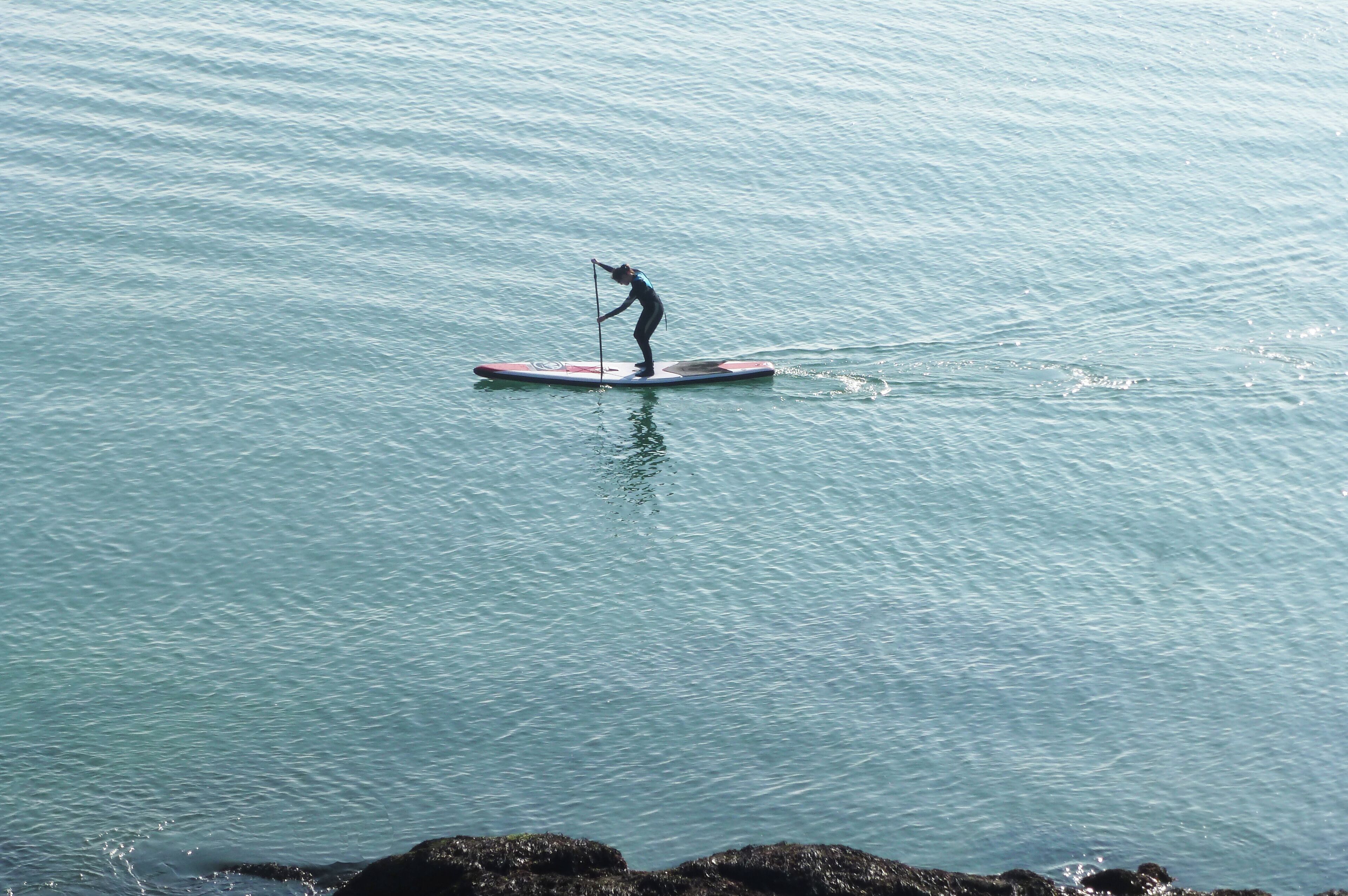 A person paddleboarding on calm water.