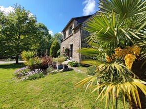 Una casa de piedra con un jardín lleno de plantas y flores.
