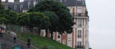 A wet street with people walking up a hill towards a row of buildings.