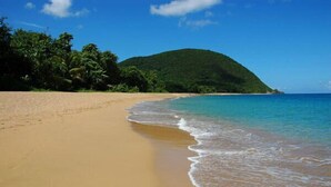 A beach with clear turquoise water, sandy shore, and a green hill in the background. - Villa Kaz Coco, sea views (Deshaies)
