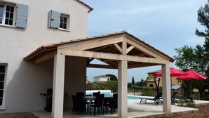 A covered outdoor patio with a pool, tables, and chairs. - Air-conditioned villa with heated pool for 9 people (La Motte)