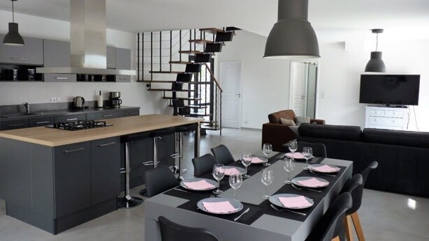 A modern kitchen with a central island, dining area with a long table set for six, and a staircase leading to another level. - Air-conditioned villa with heated pool for 9 people (La Motte)