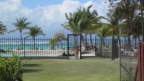 A fenced pool area with a view of the beach and ocean. - Very nice F2 facing the sea, direct access to Sainte-Anne beach, swimming pool, tennis (SAINTE ANNE)