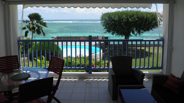 A balcony with a view of the ocean, a pool, and outdoor furniture. - Very nice F2 facing the sea, direct access to Sainte-Anne beach, swimming pool, tennis (SAINTE ANNE)