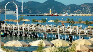 A beachside pier with rows of sun loungers and umbrellas, a sign indicating 'B. BEACH', and a lighthouse in the background. - NEW !! ''CANNES-CENTER'' Cosy  high standing apartment in the heart of Cannes (Cannes)