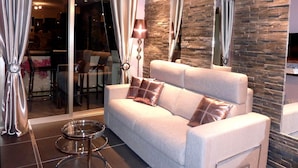 A modern living room with a sofa, a glass table, and a stone accent wall. - NEW !! ''CANNES-CENTER'' Cosy  high standing apartment in the heart of Cannes (Cannes)