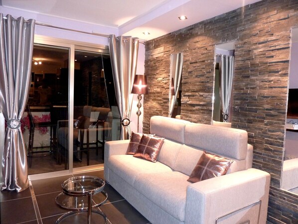 A modern living room with a sofa, a glass table, and a stone accent wall.