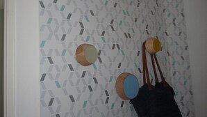 A room with a patterned wallpaper, a white ceiling light fixture, and two wooden wall decorations. - Casa Estrella - Marseille hypercentre ❤️ (Marseille)