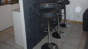 A small kitchen area with a bar counter, two stools, and a hanging light fixture. - Casa Estrella - Marseille hypercentre ❤️ (Marseille)