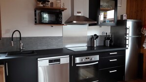 A modern kitchen with a dishwasher, oven, microwave, and stainless steel appliances. - Very pretty semi-detached chalet, all comforts, close to the Chantemerle slopes  (Saint-Chaffrey)