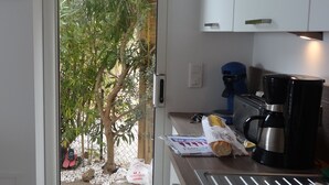 A kitchen with a view of a garden through a glass door. - MAZET with superb sea view and beautiful terrace - 500 m beach (Rayol-Canadel-Sur-Mer)