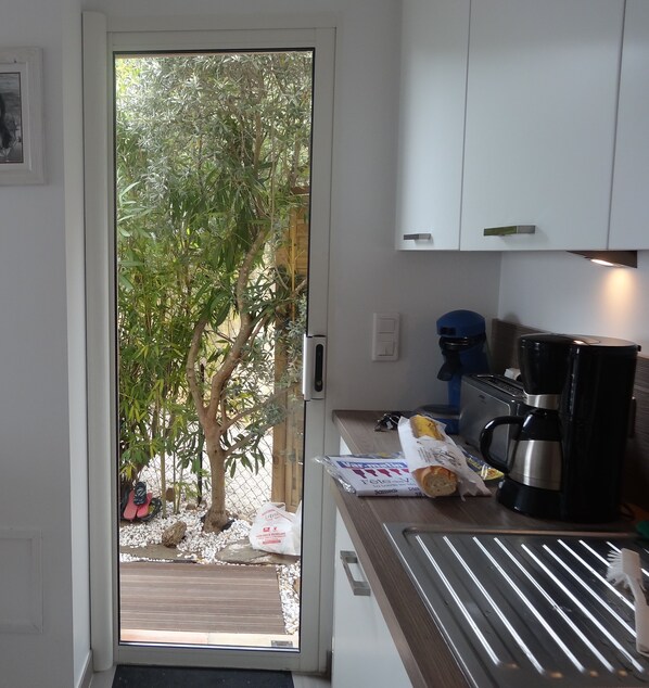 A kitchen with a view of a garden through a glass door.