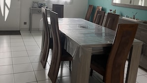 Zona pranzo con tavolo, sedie, lampadario a soffitto, una finestra e uno specchio fissato al muro.