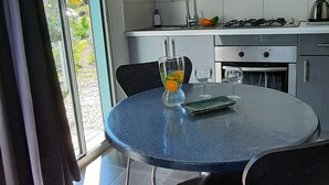 Et moderne køkken med lysegrå skabe, en gasblus og et rundt bord med stole.