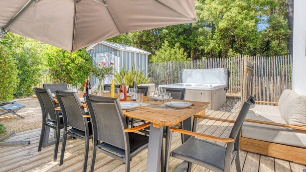 Un área de comedor al aire libre con una mesa, sillas y una sombrilla.