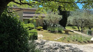 A traditional building with a tiled roof, surrounded by lush greenery and a stone pathway. - Nyons, charming villa in a green setting  (Nyons)