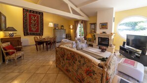 A living room with a fireplace, television, dining area, and a large window. - Nyons, charming villa in a green setting  (Nyons)
