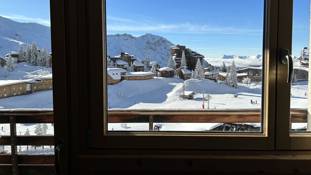 En snötäckt bergsby med traditionella trähus och en klarblå himmel.