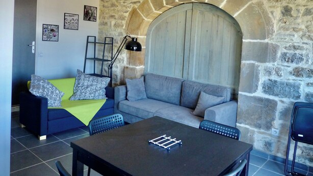 A living room with a stone wall, a grey sofa, a black table, and a blue armchair.