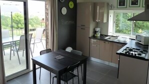 A modern kitchen with a dining area, a gas stove, and a large window. - Cottage at the Mirande farm near Rocamadour, Padirac, Collonges la rouge (Queyssac-Les-Vignes)