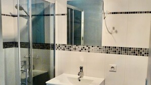 A bathroom with a glass-enclosed shower, a white sink with a mirror above it, and a toilet.