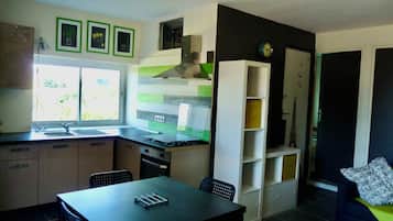 Eine kleine Küche mit Fenster, ein Essbereich mit Tisch und Stühlen sowie eine Wohnbereich mit einer Couch.