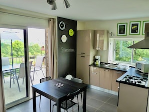 A modern kitchen with a dining area, a view of the outdoors, and a blackboard with 'Bienvenue' written on it. - Cottage at the Mirande farm near Rocamadour, Padirac, Collonges la rouge (Queyssac-Les-Vignes)