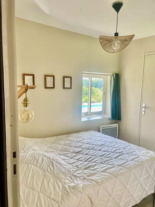 A bedroom with a bed, a window with curtains, a radiator, and wall-mounted light fixtures. - Cottage at the Mirande farm near Rocamadour, Padirac, Collonges la rouge (Queyssac-Les-Vignes)