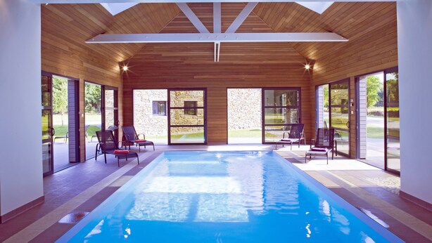 An indoor swimming pool with wooden ceiling beams, large windows, and outdoor seating. - Gîte for 6 people with heated indoor pool - Gîtes de France 5 épis (Carentoir)