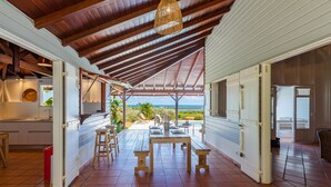 Un amplio patio con mesa y sillas, una zona de cocina con fregadero y armarios, y vista al océano.