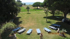 A grassy outdoor area with lounge chairs and a hammock, overlooking a beach. - Villa MALYMA direct beach access (Zahora)