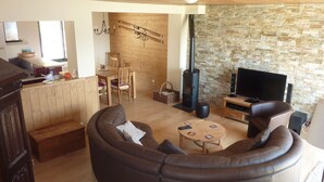 Ein gemütliches Wohnzimmer mit einer gebogenen Couch, einem Fernseher, einer Steinwand und einem Kamin.