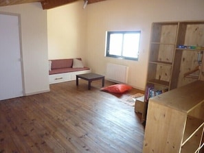A room with a wooden floor, a sofa with cushions, a small table, a window, and a wooden bookshelf. - Large Chalet in Angles with magnificent view of lake and mountains, classed 4 * (Les Angles)