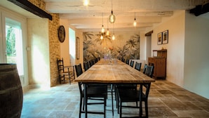 A long wooden dining table with chairs, a stone barrel, and a mural of palm trees on the wall. - Exclusive Hamlet and XXL Pool (Vergt)