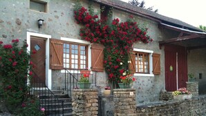 A rustic stone building with wooden shutters, a stone staircase, and a flower box on the steps. - Mansion (Saint-Germain-Des-Champs)