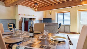 A dining area with a wooden ceiling, a fireplace, and a television. - Mansion (Saint-Germain-Des-Champs)