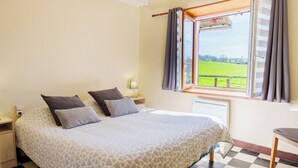 A bedroom with a bed, a window with curtains, a checkered floor, and a view of a green field. - Mansion (Saint-Germain-Des-Champs)
