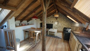 Een landelijke keuken met houten balken, een stenen muur en een eethoek met een tafel en stoelen.