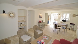 A spacious living area with wicker furniture, a dining table, and a red couch. - Farmhouse in the middle of the Provence  (Moustiers-Sainte-Marie)
