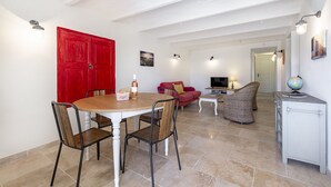 A spacious living area with a round wooden table, red door, and a television. - Farmhouse in the middle of the Provence  (Moustiers-Sainte-Marie)