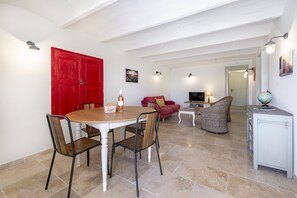 A spacious living area with a round wooden table, red door, and a television.