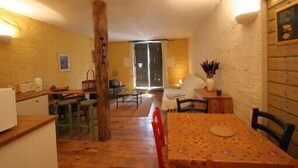Una habitación acogedora con una mesa de comedor de madera, sillas, una barra con taburetes y un ventanal que proporciona luz natural.