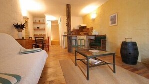 Una habitación acogedora con una cama, una mesa de madera, una silla, una zona de cocina y un barril grande.