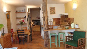 Una cocina acogedora con mobiliario de madera, un comedor y un vano que da a otra habitación.