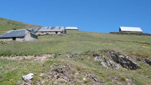 Un paysage rural avec des bâtiments en pierre et un ciel bleu dégagé.